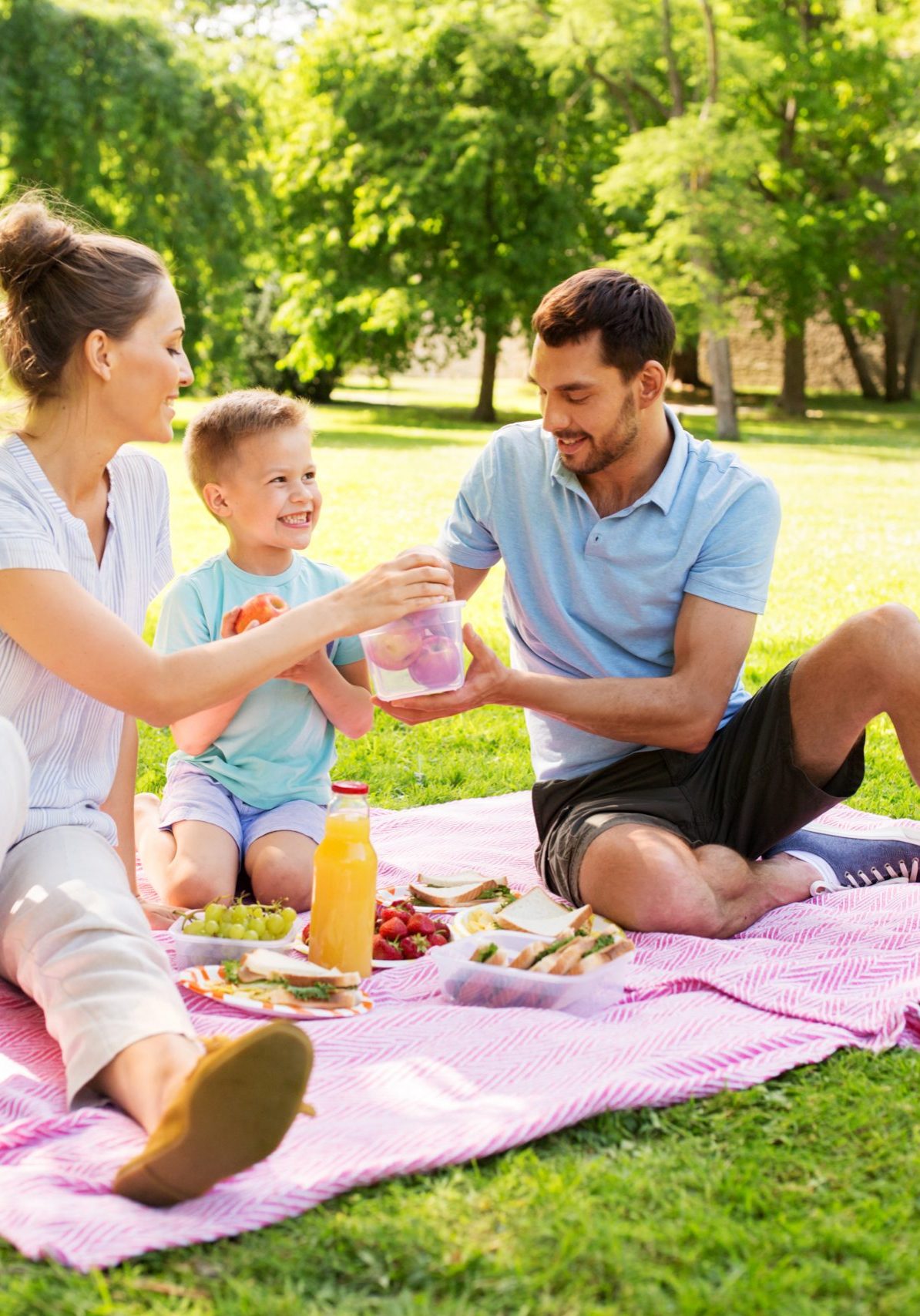 family, leisure and people concept - happy mother, father and little son having picnic at summer park